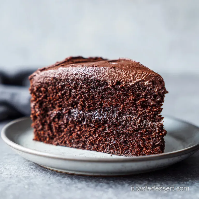 Elegant slice of dark chocolate cake on a white plate, topped with a swirl of cream and chocolate shavings.