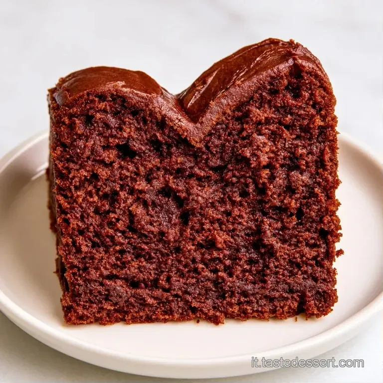 Dolce rosso a cuore su piatto bianco, decorato con gocce di coulis di lampone lucido e un rametto di menta fresca.